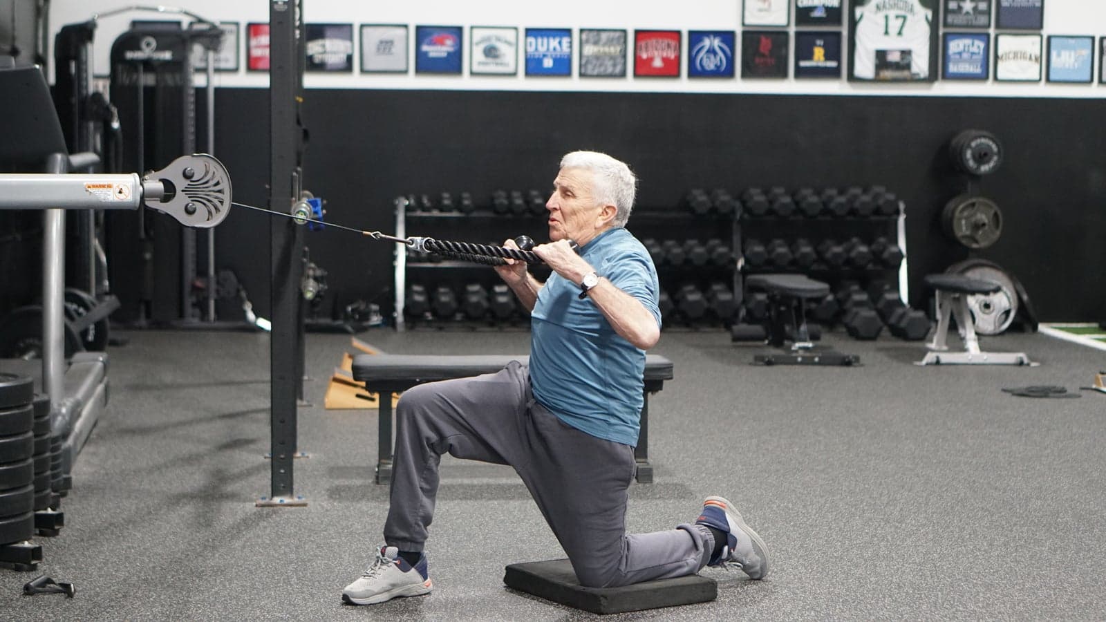 An older golfer does a kneeling cable row
