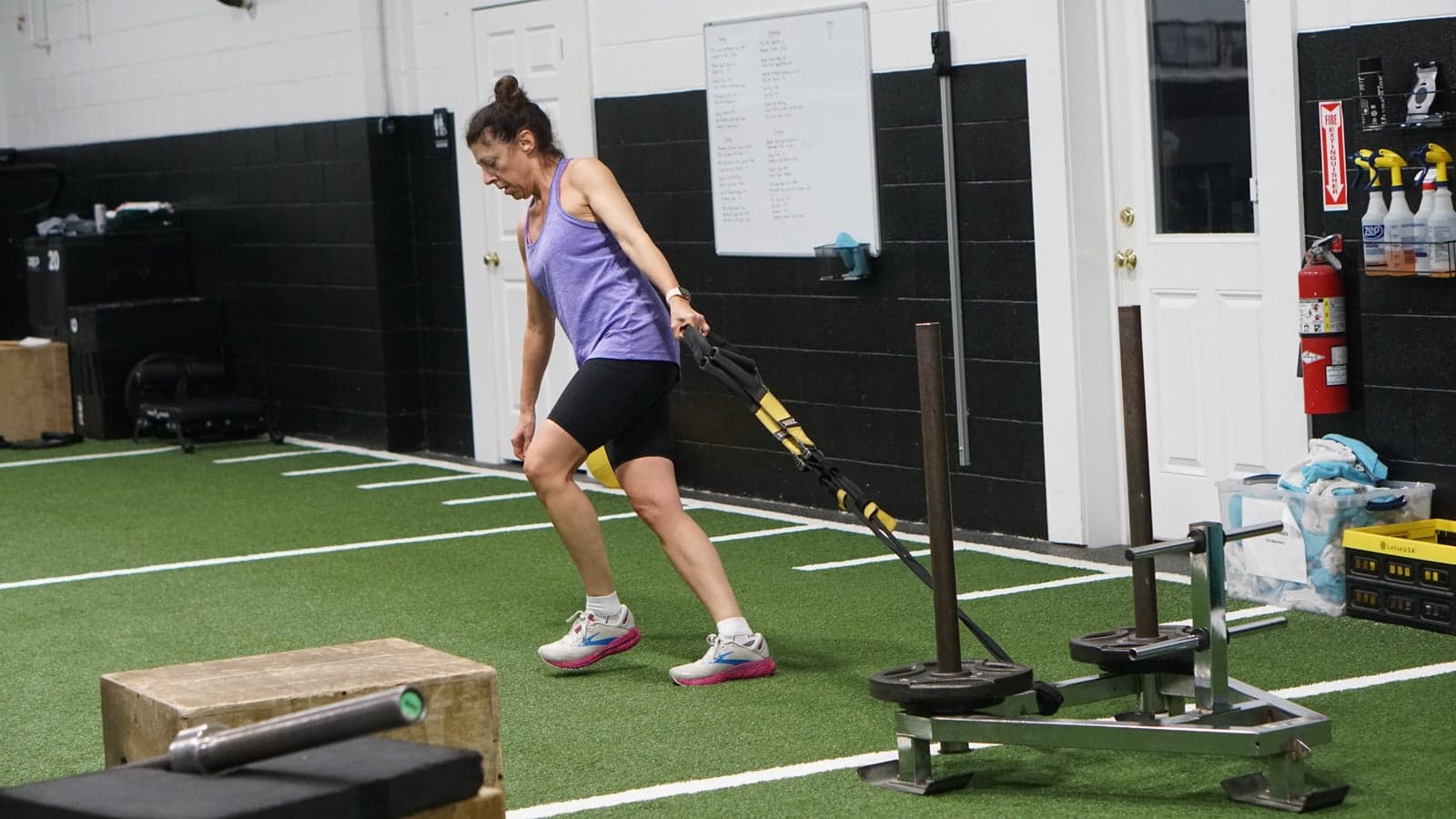 A member pulls a weighted sled across the turf